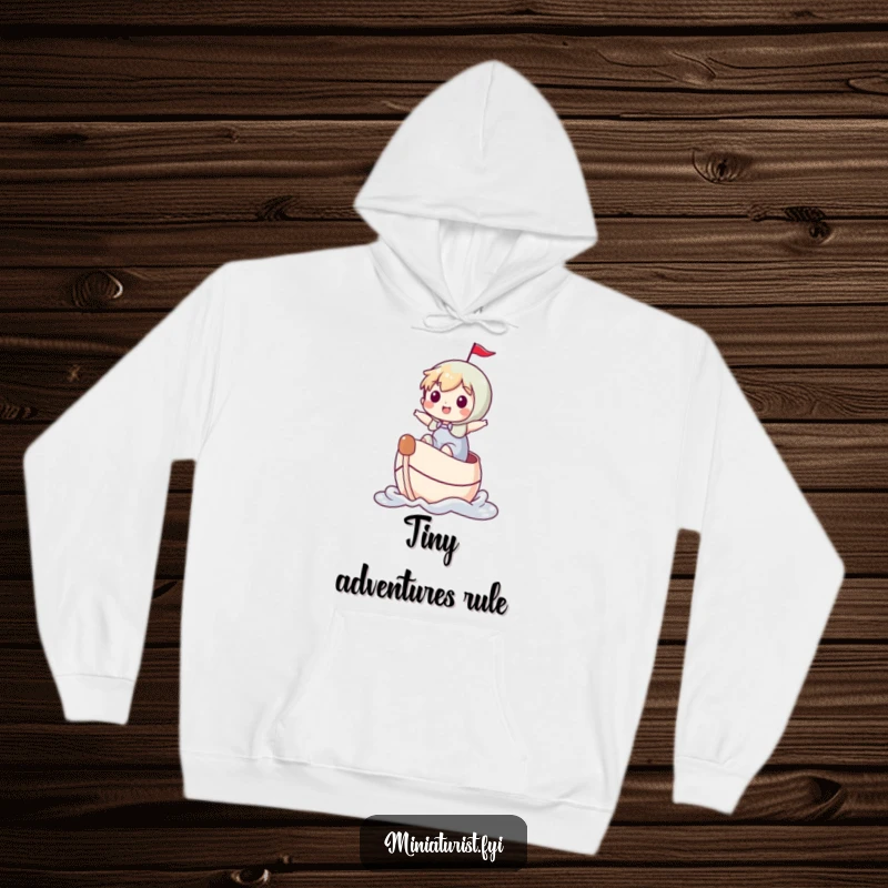 Funny miniature character joyfully navigating a thimble boat, featured on a cozy hoodie, symbolizing grand journeys.